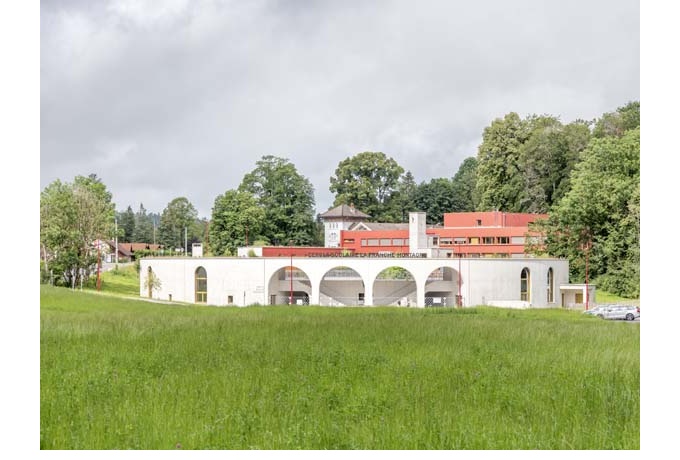 l’ensemble scolaire dans son contexte paysager. En arrière-plan, le bâtiment réhabilité, repeint en rouge.<br/> Crédit photo : BOEGLY Luc